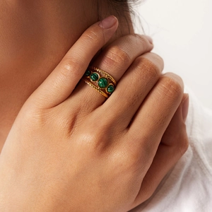 Close-up of gold stainless steel ring featuring four green malachite stones on model's hand