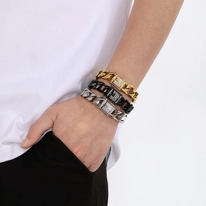 Close-up of gold, black, and silver Cuban link bracelets with pavé zircons on model