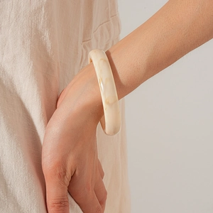 Detail view of cream marbled resin bangle with natural texture on a model's wrist