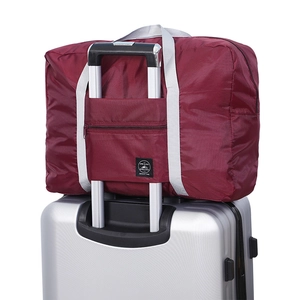 Burgundy foldable travel bag with trolley sleeve on silver suitcase handle