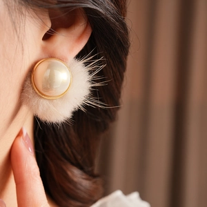 Detailed close-up of retro pearl earrings with white fur trim and golden metal edges