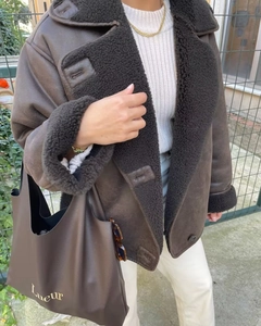 Détail de la veste en peau lainée marron foncé avec bordure noire et texture cuir