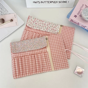Close-up of pink checkered roll-up makeup brush bag with slots and floral pattern