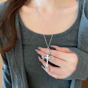 Detailed view of silver cross pendant with intricate relief patterns on model's neck