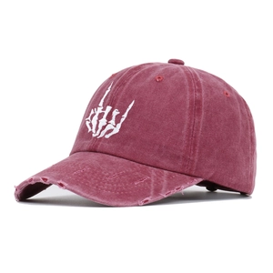 Close-up of distressed ripped details and skull hand embroidery on washed burgundy cotton cap