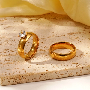 Vergoldetes Edelstahl-Ring-Set mit rundem Zirkonia auf beigem Stein präsentiert