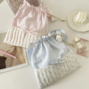 Detail of pink and blue striped drawstring tote bags with bow and heart charms