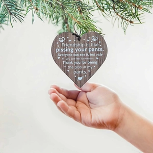 Close-up of heart-shaped wooden friendship ornament hanging on a Christmas tree branch