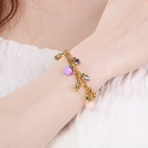 Gold chain bracelet with colorful fruit zircon charms and heart pendant on wrist