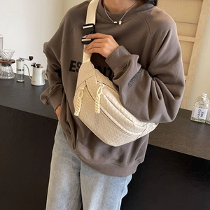 Beige woven chest bag for men and women with adjustable strap in a stylish cafe setting