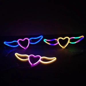 Détail des enseignes néon ailes de cœur à LED en rose, bleu et jaune dégradé
