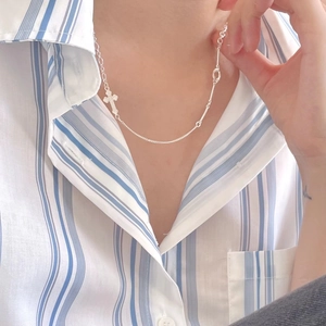 Minimalist 925 sterling silver cross pendant necklace on a blue striped shirt background