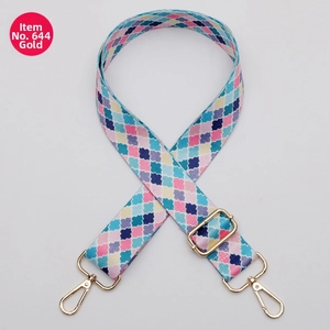 Detail of a 38mm wide adjustable fabric bag strap with colorful clover pattern and gold clips
