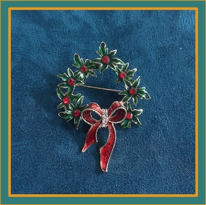 Detail of Christmas wreath brooch with green enamel leaves and red crystal bow