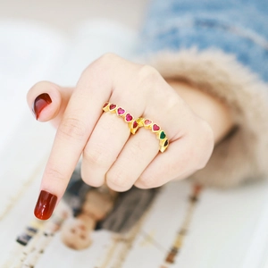 Close-up of golden ring with colorful heart-shaped cubic zirconia on woman's finger