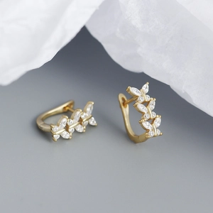 Macro shot of gold-plated U-shaped earrings with marquise-cut zircons and butterfly motifs