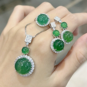 Close-up of green chalcedony jewelry set including necklace, ring, and earrings on model