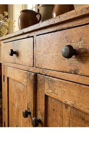 Close-up of vintage cast iron drawer handles on a rustic solid wood storage cabinet