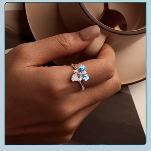 Elegant s925 silver open ring with blue iris flower worn by a hand holding a cup
