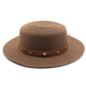 Chapeau de paille marron à calotte plate avec ruban en cuir et rivets dorés sur fond blanc