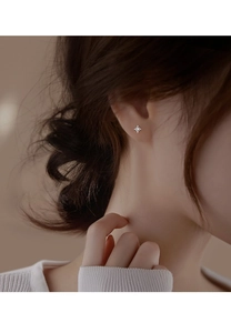 Macro close-up of a minimalist S925 sterling silver four-pointed star earring with zircon