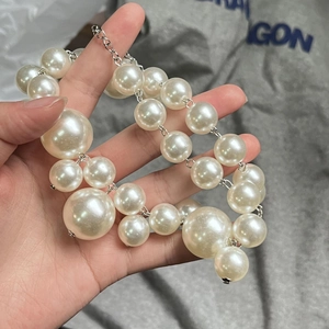 Detailed view of layered faux pearl necklace with oversized beads and silver chain
