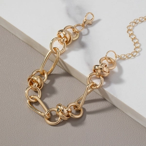 Men's trendy gold chain bracelet with knot links and oval rings on marble background