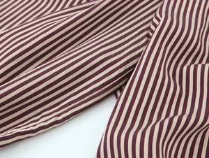 Makrodetail des weinrot gestreiften Stoffes mit weicher Textur und fallender Qualität