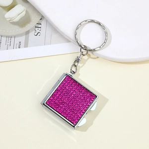Detailed close-up of a silver square keychain set with sparkling pink rhinestones
