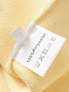 Detail of yellow knit texture and garment tag showing 100% polyester material composition
