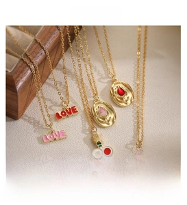 Détail de colliers plaqués or avec roses en émail coloré et pendentifs lettres d'amour