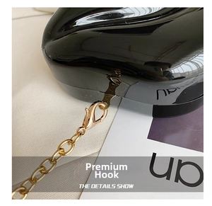 Detail of high-gloss black leather bag showing the premium golden metal chain and hook