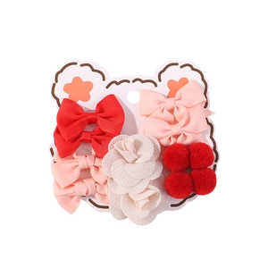 Detailed view of kids hair accessories set with red bows and flowers on bear card