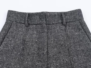Macro view showing herringbone texture and stitching on dark grey trouser waist belt loops