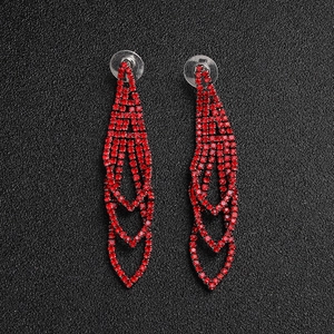 Detail of tiered red crystal tassel earrings with sparkling rhinestones on black background