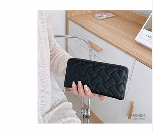 Detailed view of women's long black woven leather wallet with gold zipper closure