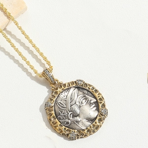 Detail of vintage pharaoh coin pendant with silver relief and gold twisted border