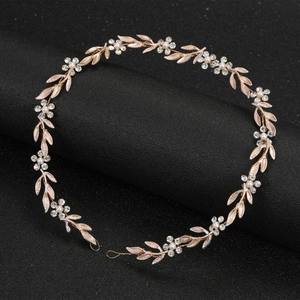Détail d'un serre-tête de mariée or rose avec strass et perles sur support noir