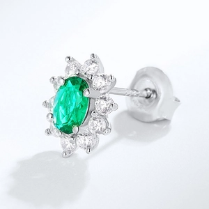 Macro view of emerald green oval cut earrings with halo white crystal details