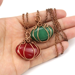 Close-up of handmade wire wrapped pumpkin pendant necklaces with red and green stones