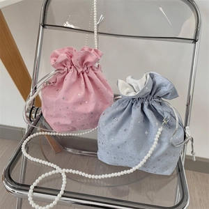 Detail of canvas drawstring crossbody bags with star patterns and pearl chain straps
