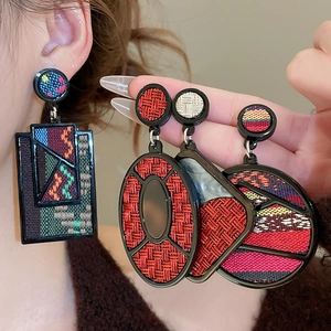 Detailed view of woven geometric earrings featuring colorful bohemian patterns and textures