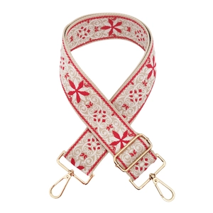 Detail of wide jacquard bag strap with red floral embroidery and gold metal hardware