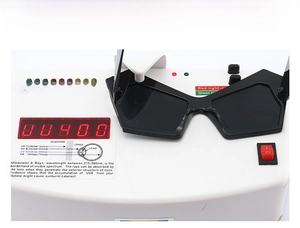 Detailed UV400 protection test showing black irregular sunglasses on a digital tester