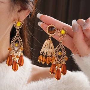 Detail of vintage gold tassel earrings with amber tiger eye stones and rhinestone accents