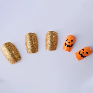 Unghie finte per Halloween con zucche e glitter dorati di media lunghezza