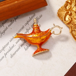 Vintage Aladdin magic lamp brooch with orange enamel and gold finish on retro paper