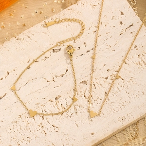 Vue détaillée d'un ensemble de bijoux coeur doré avec collier et bracelet sur pierre