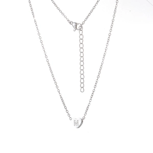 Vue macro du pendentif cœur argenté avec gravure M et chaîne fine à fermoir ajustable