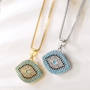 Gold and silver Evil Eye necklaces with blue cubic zirconia on textured shell background